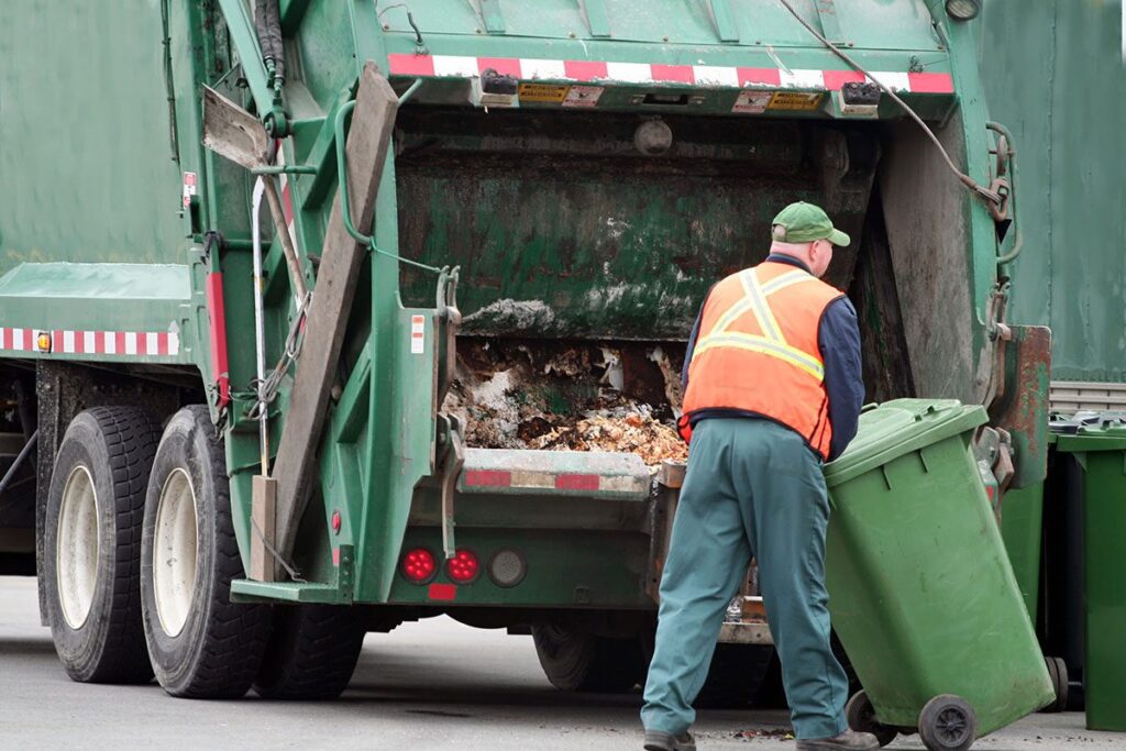 Dublin city council operation waste house project - man loading dustbin waste into a truck