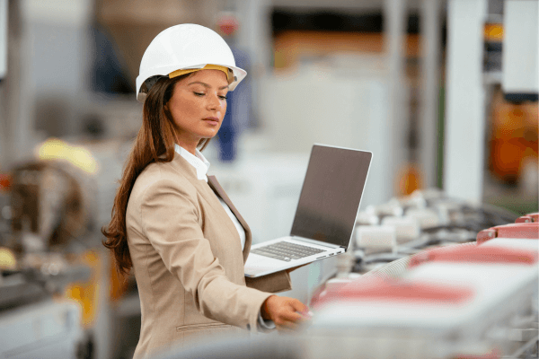 What is a quality audit –woman in white hard hat in factor with laptop doing a quality inspection