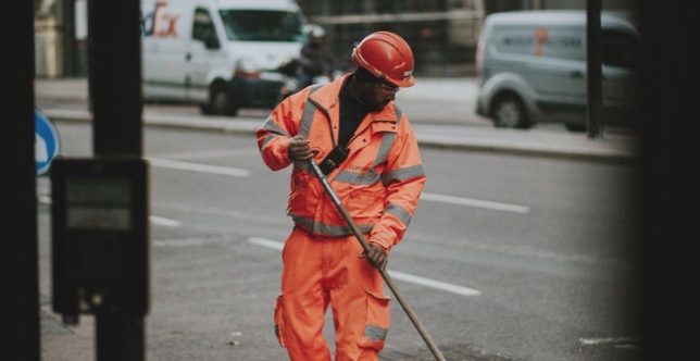 A lone worker sweeping a street